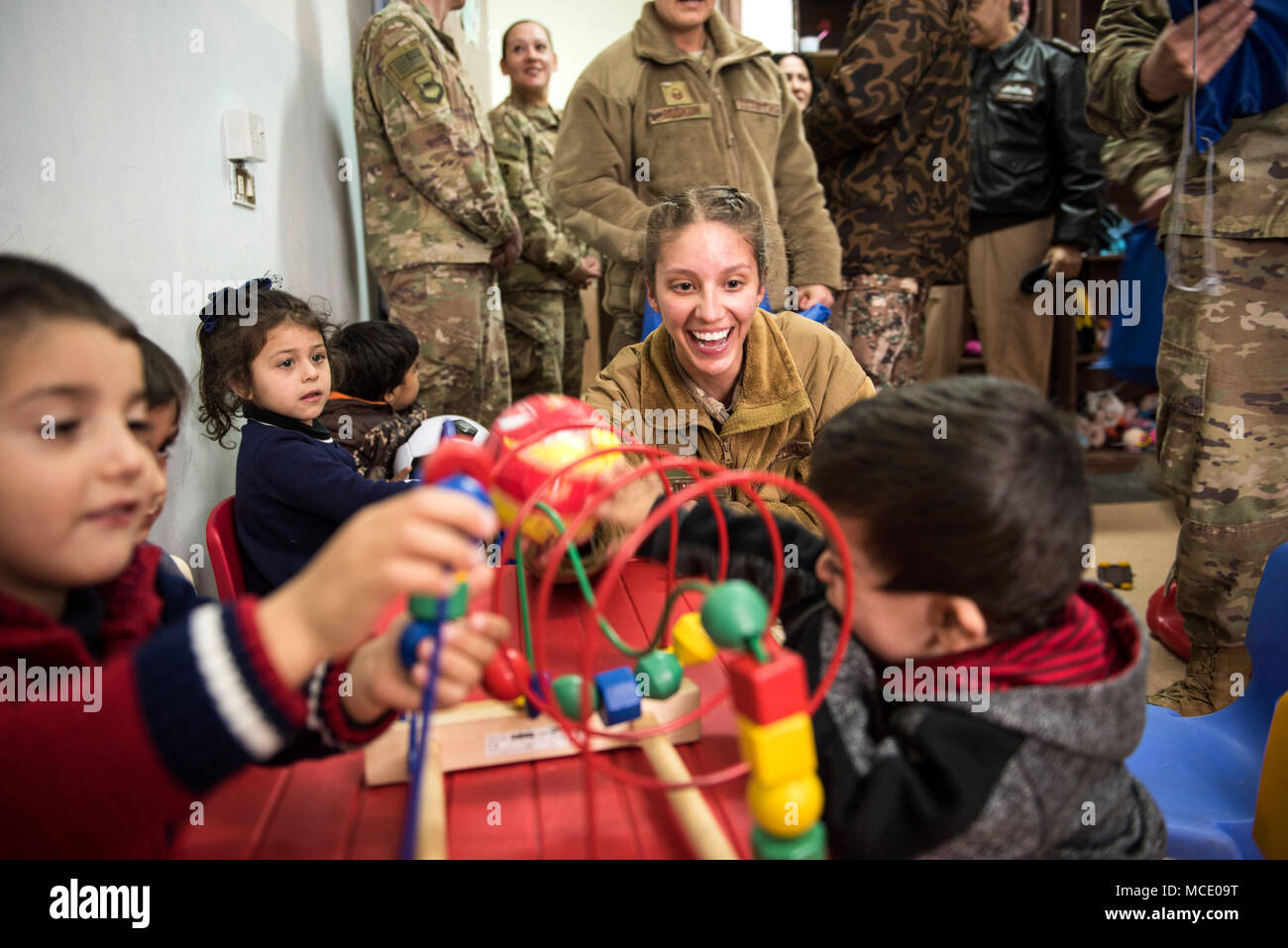 Senior Airman Maria Lopez, assigned to the 332d Expeditionary Security Forces Squadron, plays with children during a donation drop-off February 26, 2018, at an undisclosed location. Service members gathered and delivered supplies in their spare time as they work towards Operation Inherent Resolve objectives. (U.S. Air Force photo by Staff Sgt. Joshua Kleinholz) Stock Photo
