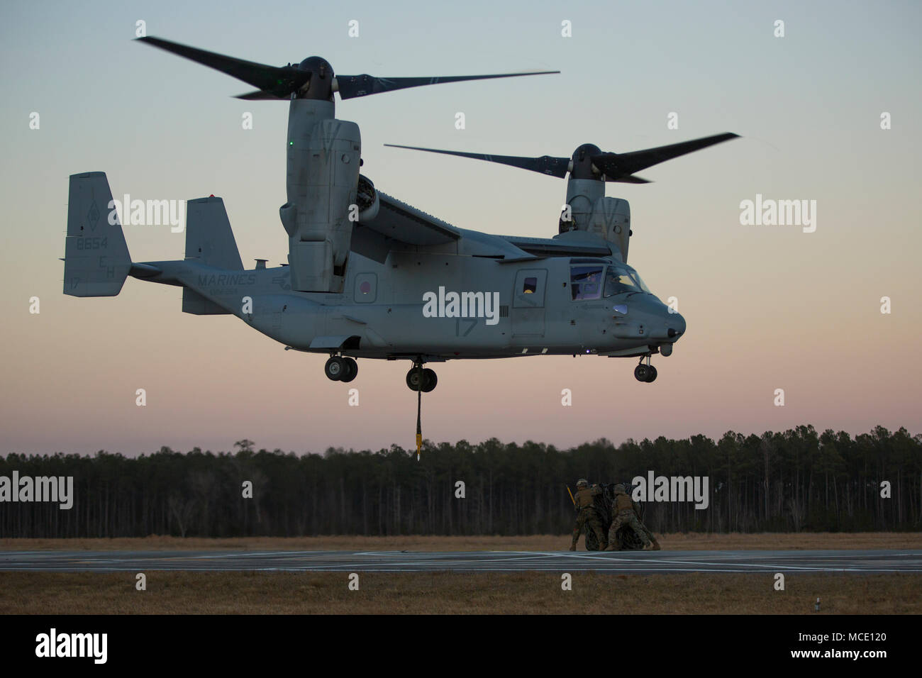 A U.S. Marine helicopter support team with 2nd Transportation Support Battalion, Combat Logistics Regiment 2, 2nd Marine Logistics Group prepare to attach cargo to an MV-22 osprey as part of an external lift drill at a drop zone on Camp Lejeune, N.C., Feb. 22, 2018. The drills simulated transporting supplies to and from designated areas safely and efficiently. (U.S. Marine Corps photo by Lance Cpl. Ashley McLaughlin) Stock Photo