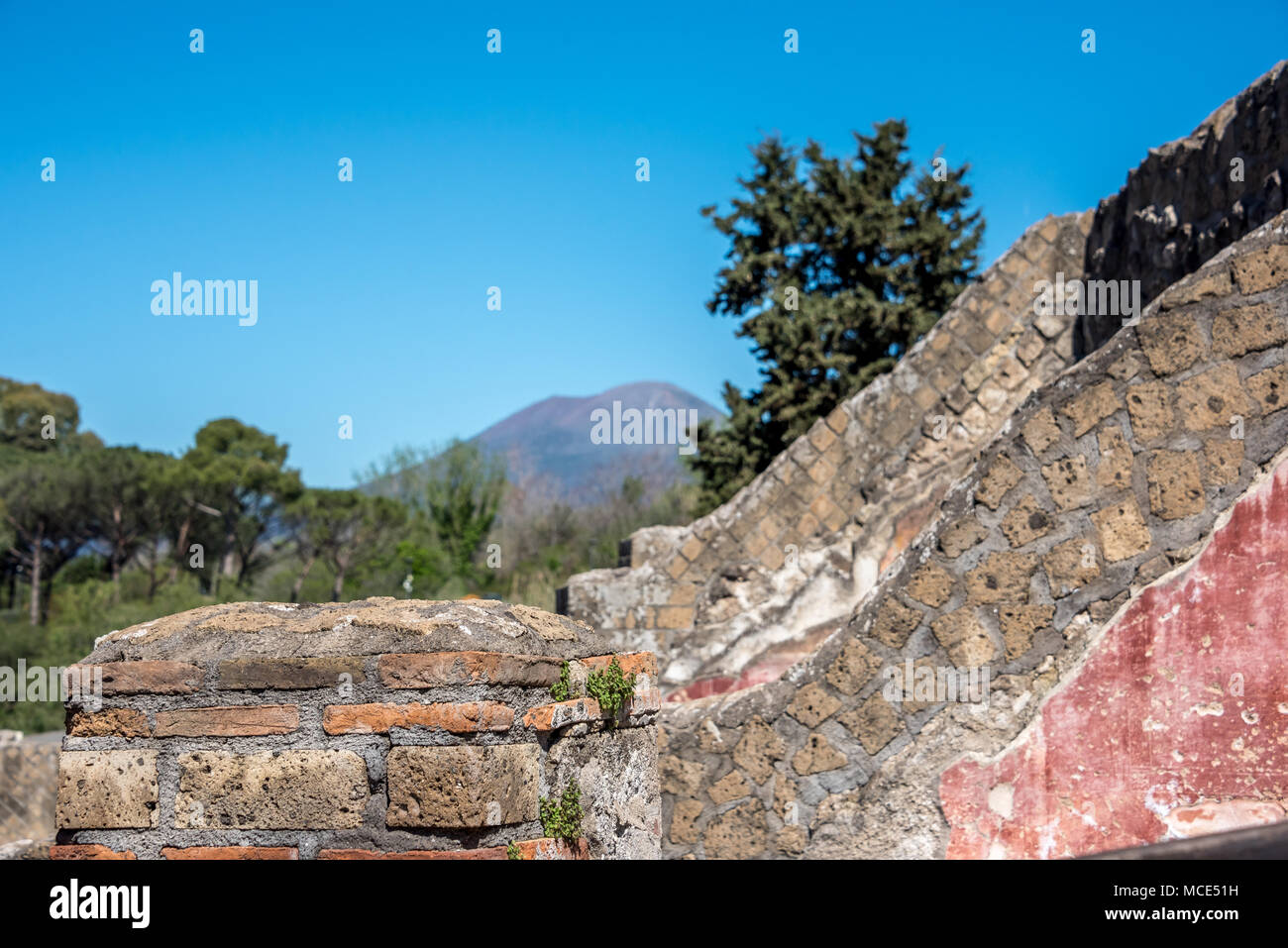 Layers of history in exposed brick walls and remaining fresco at Pompeii with Mt. Vesuvius volcano in background, Pompeii Archaeological Park, Italy. Stock Photo