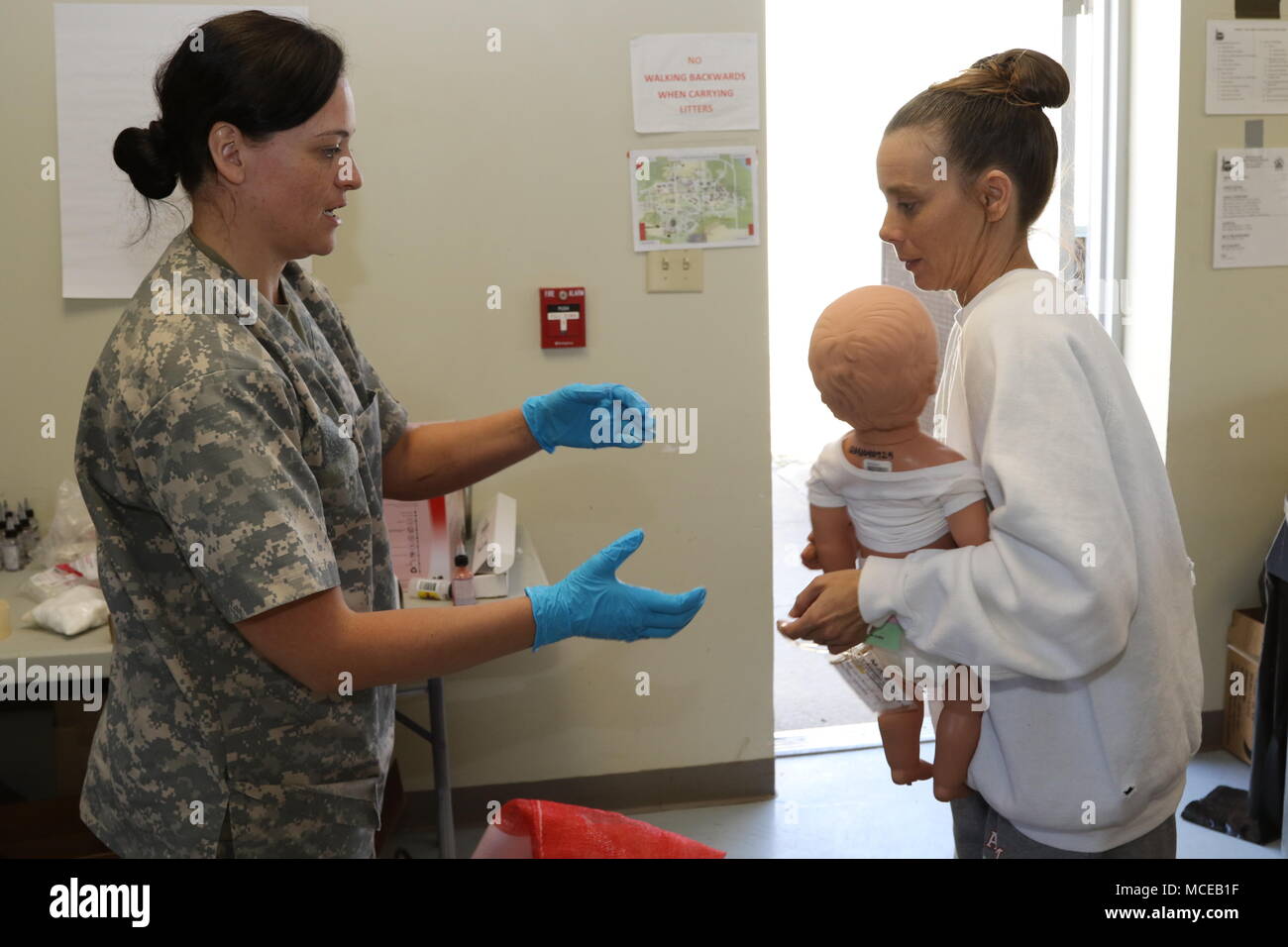 Spc. Jennifer Rosas, a chaplain's assistant with the 319th Signal Battalion, based in Sacramento, Calif., takes a baby mannequin from a displaced civilian role player to paint simulate burns on it during Guardian Response 18 at Muscatatuck Urban Training Center, Ind., April 11, 2018. More than 4,500 Soldiers from 80 units across the country are participating in Guardian Response 18. This is a multi-component training exercise with active-duty elements of the XVIII Airborne Corps as well as members of the Michigan Army National Guard.   (U.S. Army Reserve Photo by Staff Sgt. Carolyn Hawkins) Stock Photo