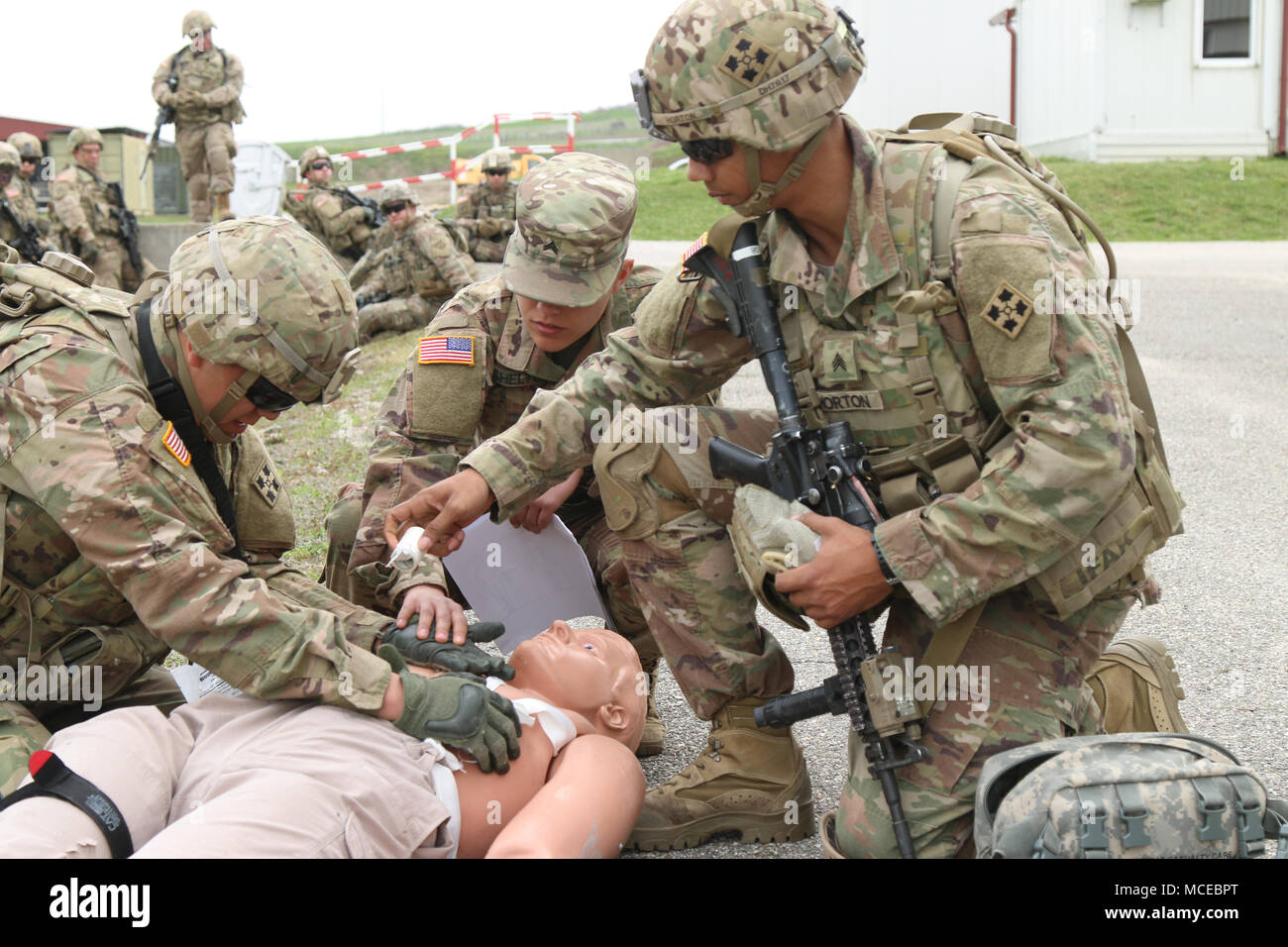 Cpl. Sarah Shelton (center) instructs Pfc. Jose Gonzales III (left) and Sgt. Deion Horton, Soldiers with the 3-61 Cavalry Regiment, 2nd Infantry Brigade Combat Team, 4th Infantry Division, to control bleeding, while bandaging a chest wound at a combat lifesaver (CLS) trauma simulation lane during a 40-hour CLS refresher course run by the Camp Marechal De Lattre De Tassigny clinic on April 11, 2018. (U.S. Army photo by Sgt. Casey Hustin, 19th Public Affairs Detachment) Stock Photo