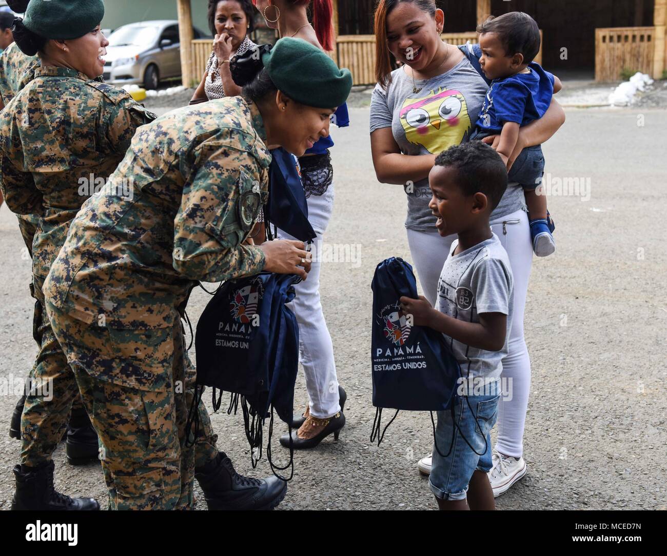 A member of the Panamanian National Border Service, known as SENAFRONT, passes bags out to children during the opening ceremony of Exercise New Horizons 2018, April 11, 2018, in Meteti, Panama. Exercise New Horizons is a joint-service training exercise, focused on enhancing relations with partner nations and providing aid to local communities while providing training U.S. military members. During the exercise, U.S. military members will build three schools, one community center and a women’s health ward in the Meteti area. They will also work closely with Panamanian health providers bringing m Stock Photo