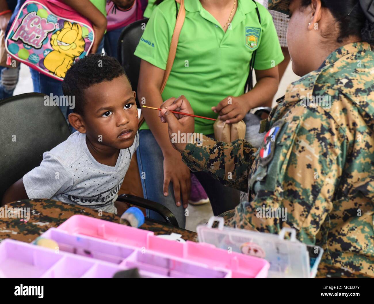 A member of the Panamanian National Border Service, known as SENAFRONT, paints the face of a child during the opening ceremony of Exercise New Horizons 2018, April 11, 2018, in Meteti, Panama. Exercise New Horizons is a joint-service training exercise, focused on enhancing relations with partner nations and providing aid to local communities while providing training U.S. military members. During the exercise, U.S. military members will build three schools, one community center and a women’s health ward in the Meteti area. They will also work closely with Panamanian health providers bringing me Stock Photo