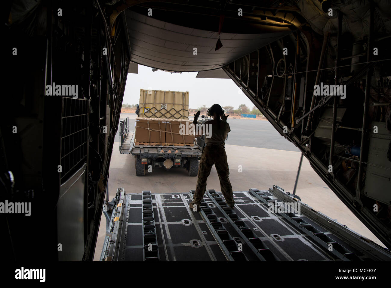 A loadmaster from the West Virginia Air National Guard motions for cargo inside a C-130H Hercules April 10, 2018 at Diori Hamani International Airport, Niger. Approximately 1,900 service members from more than 20 African and western partner nations are participating in Flintlock 2018 at multiple locations in Niger, Burkina Faso, and Senegal. Flintlock is an annual, African-led, integrated military and law enforcement exercise that has strengthened key partner nation forces throughout North and West Africa as well as western Special Operations Forces since 2005.  (U.S. Air Force photo/Senior Ai Stock Photo