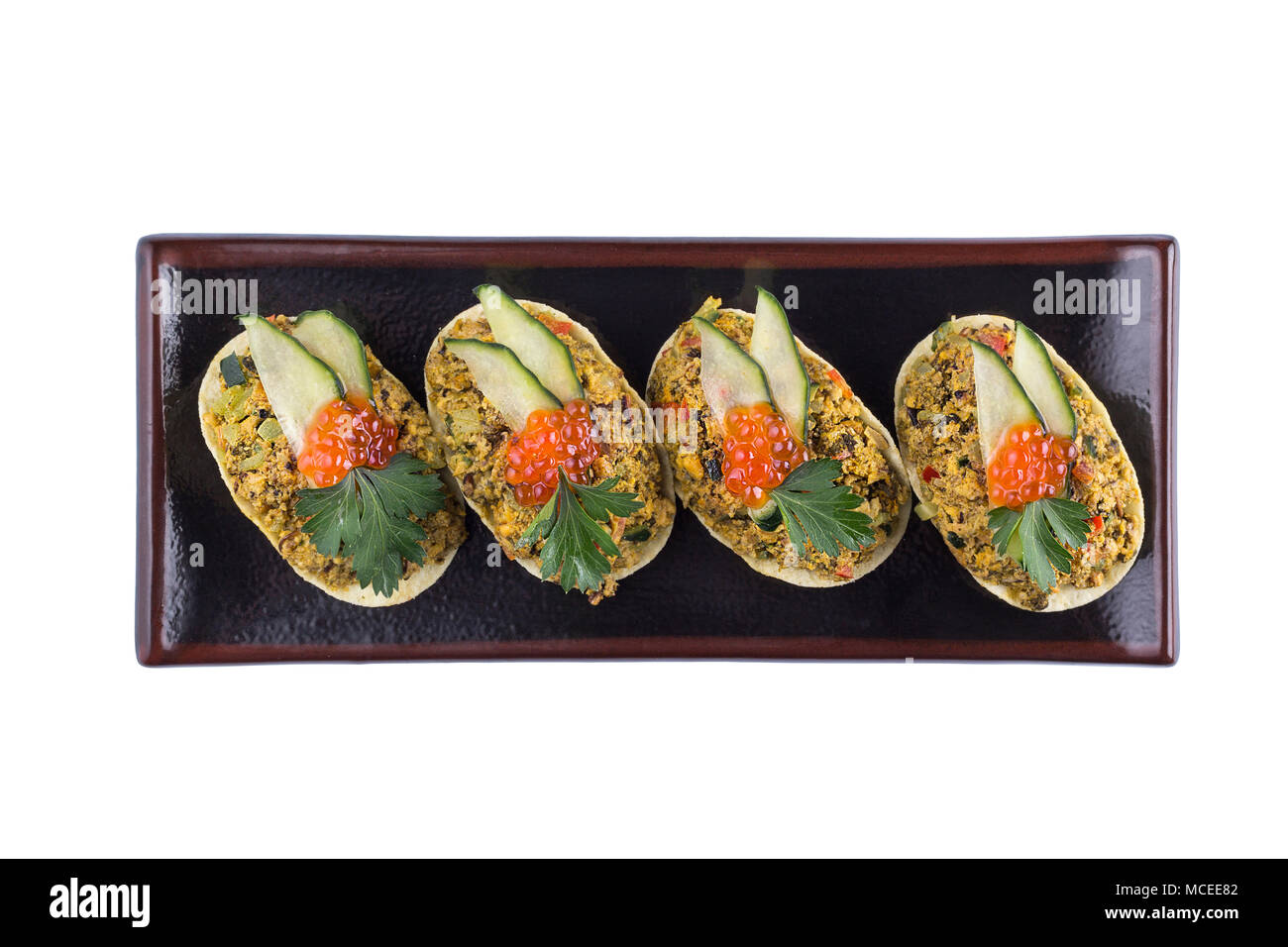 Appetizing taco appetizer with red caviar decoration. Appetizer on a white background. Isolated. Stock Photo