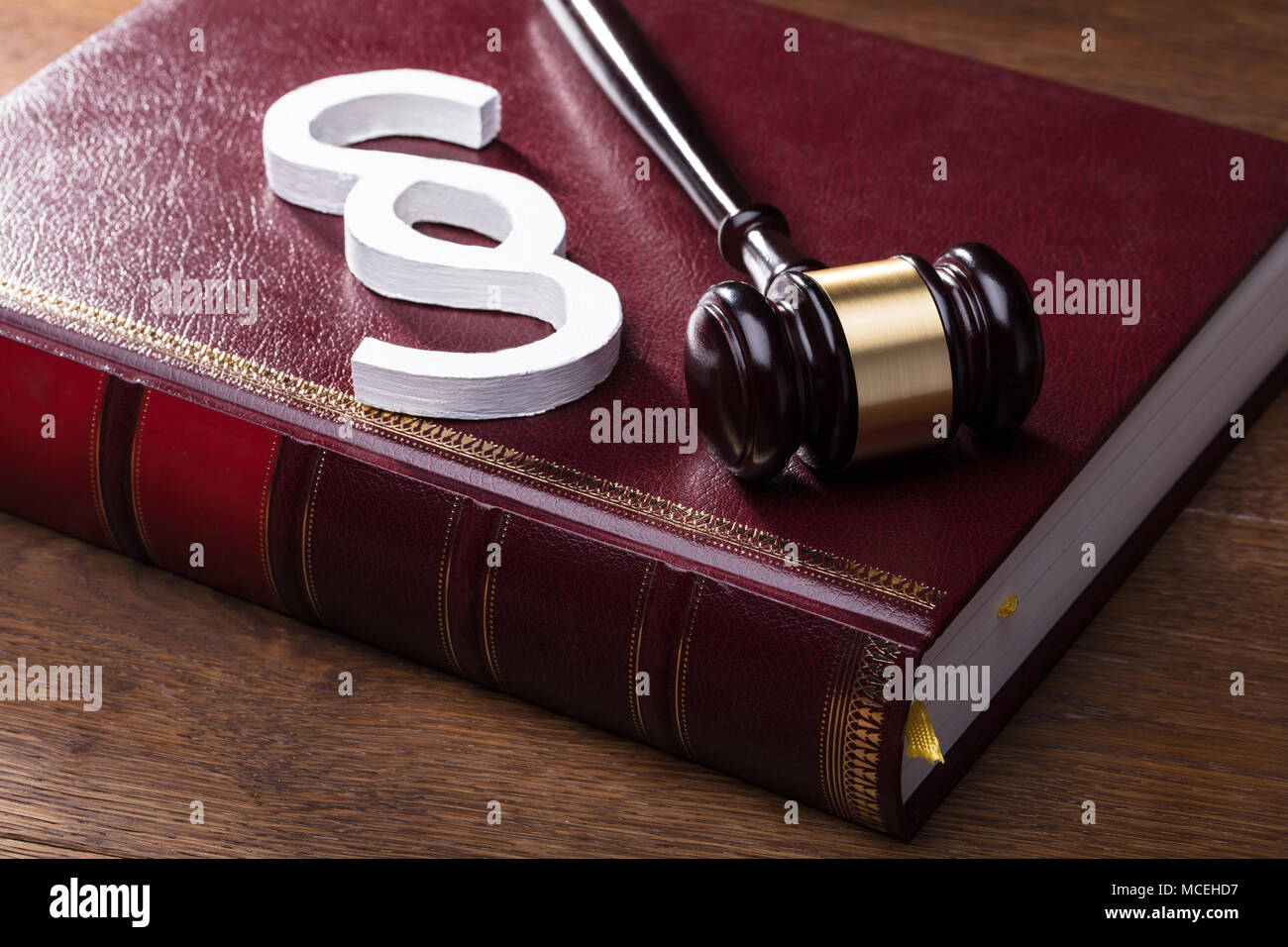 Close-up Of Big White Paragraph Symbol, Mallet And Law Book On Wooden Table Stock Photo