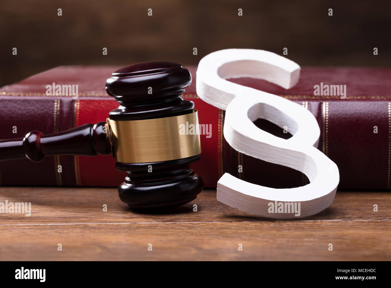 Close-up Of Big White Paragraph Symbol, Mallet And Law Book On Wooden Table Stock Photo