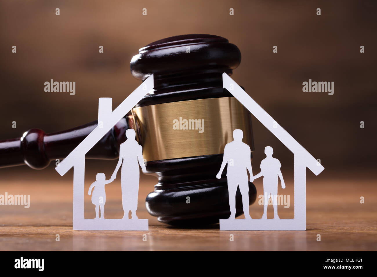 White Family Paper Cut Out In Front Of Judge Gavel On The Wooden Desk Stock Photo