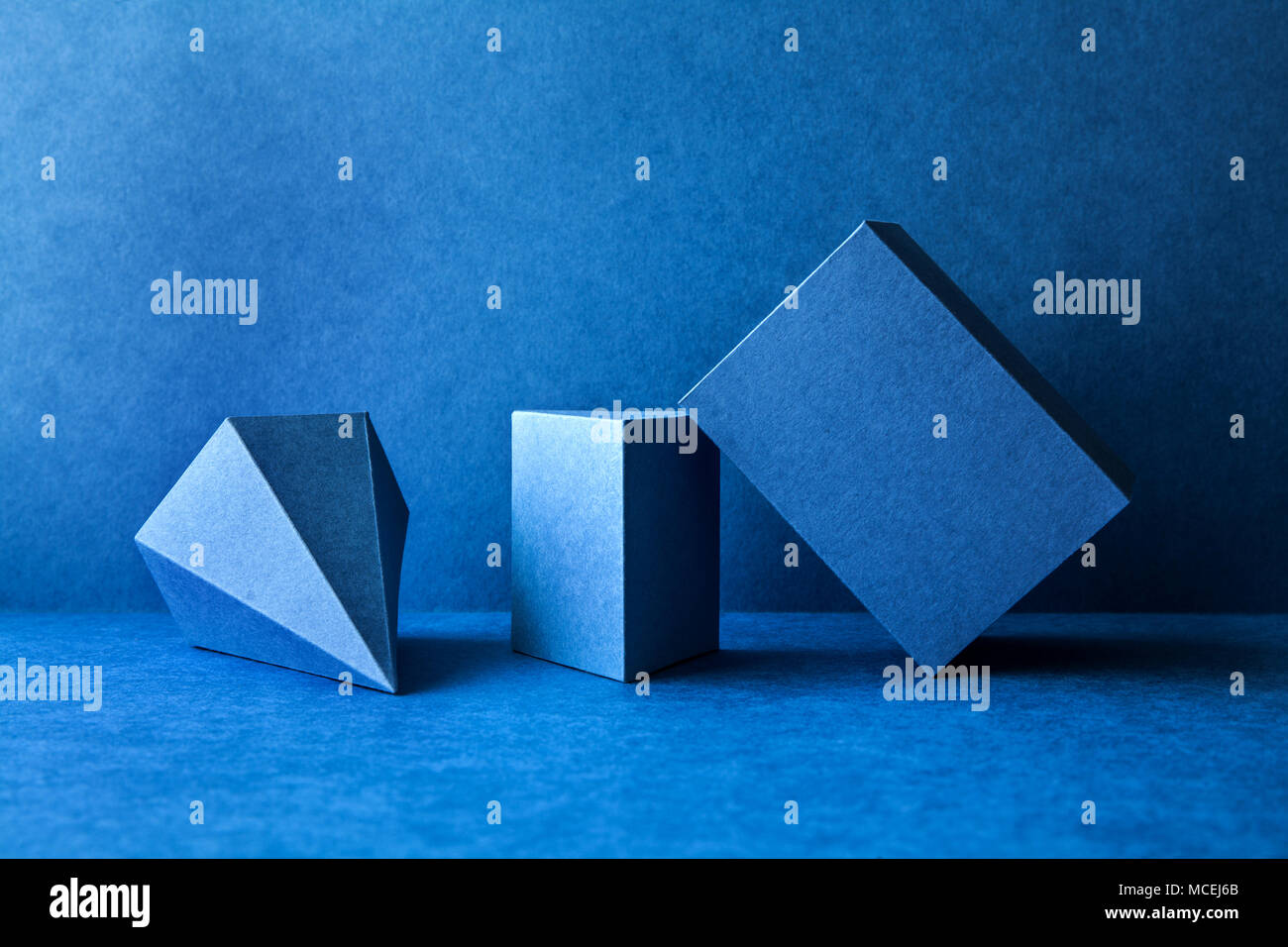 Geometrical figures still life composition. Three-dimensional prism pyramid tetrahedron rectangular cube objects on blue background. Platonic solids figures, simplicity concept photography. Stock Photo