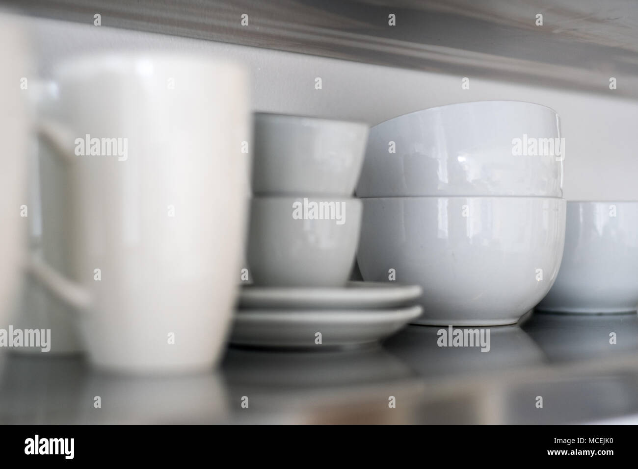 Ceramic bowls and mugs on kitchen shelf Stock Photo