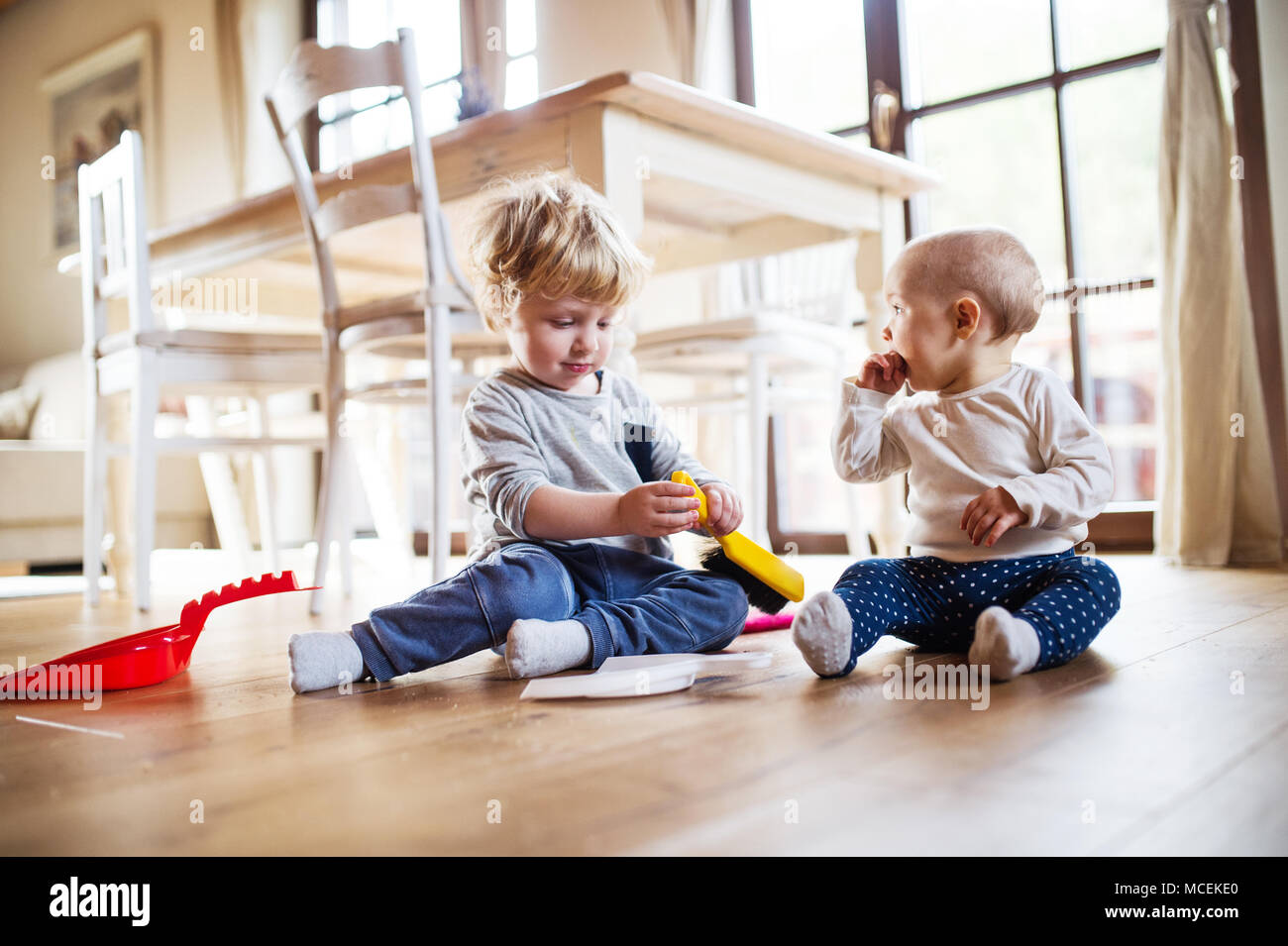 Two toddlers with brush and dustpan at home Stock Photo - Alamy