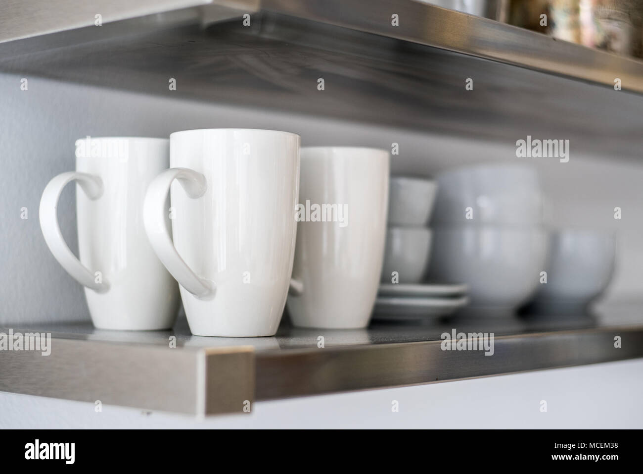 Ceramic bowls and mugs on kitchen shelf Stock Photo