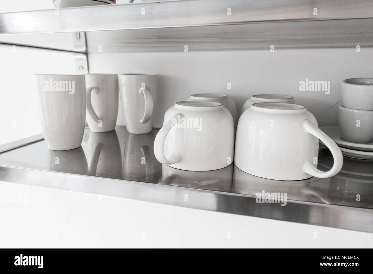 Ceramic bowls and mugs on kitchen shelf Stock Photo