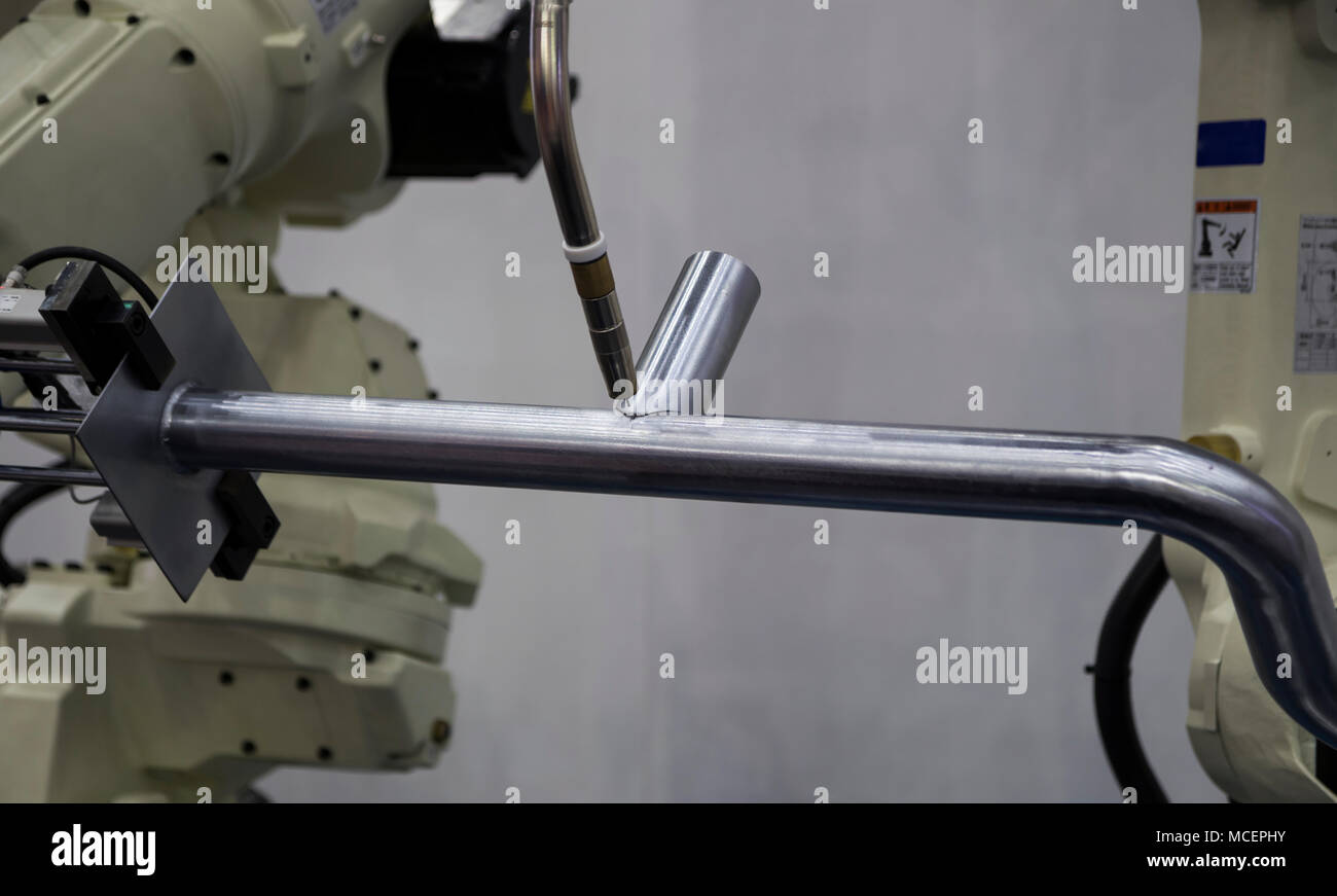Robot arm welding pipe ; focus at torch Stock Photo