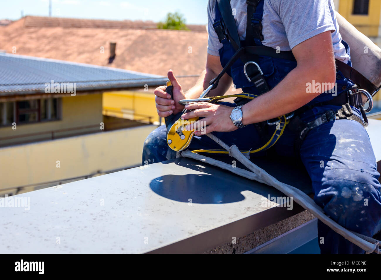 Industrial climber, alpinist, is adjusting climbing gear, preparing