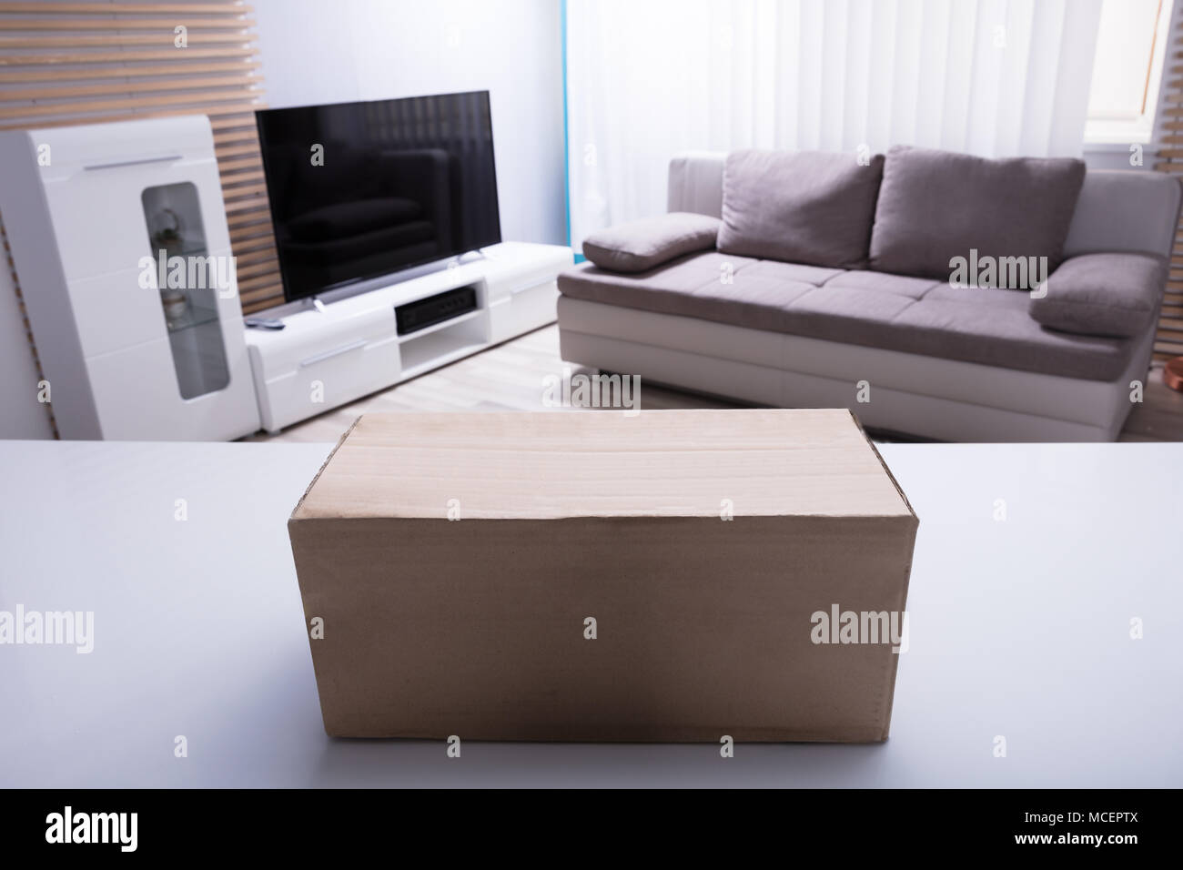 Close-up Of Cardboard Box On White Desk In Living Room Stock Photo
