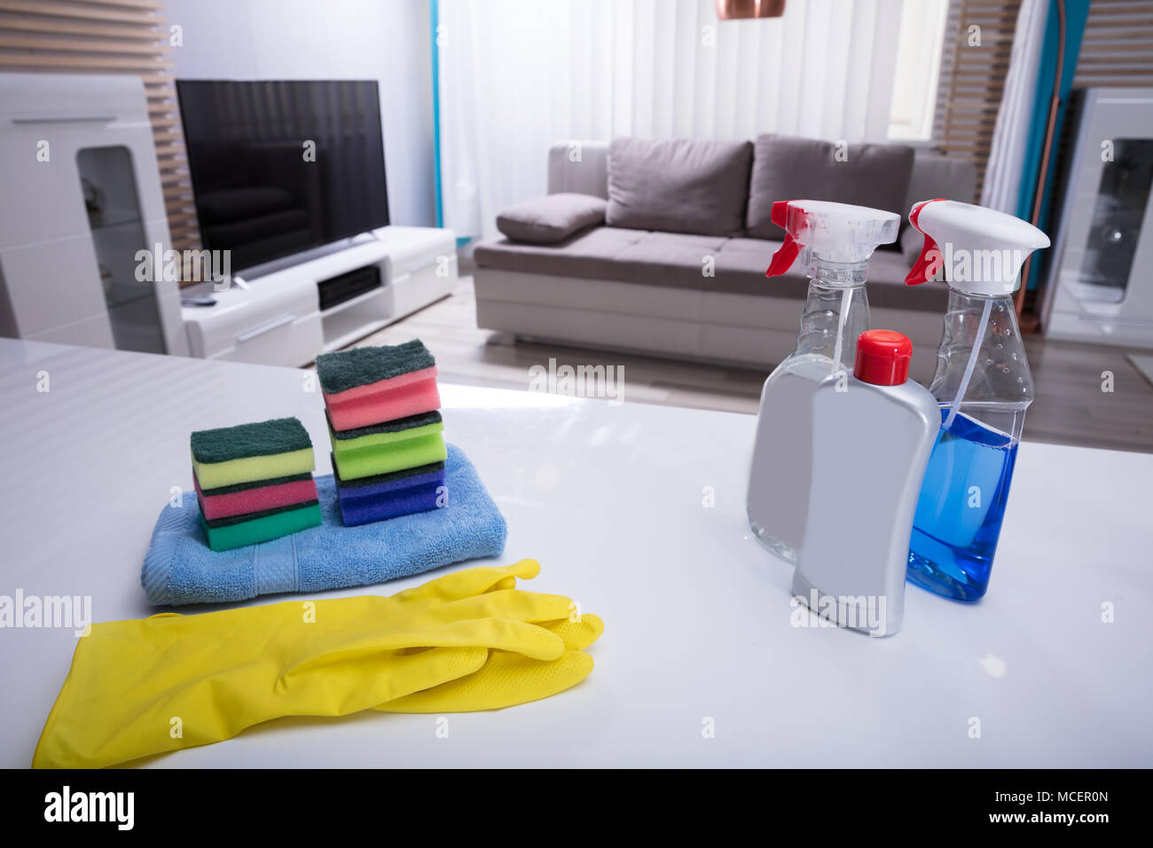 Different Cleaning Spray Bottles With Sponge And Gloves On White Desk Stock Photo