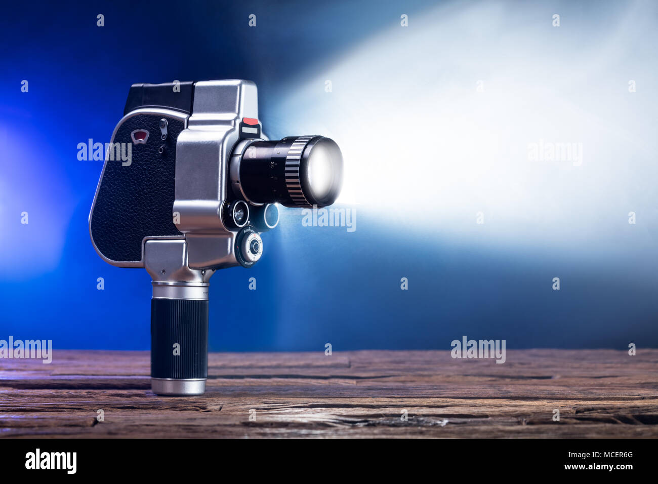 Close-up Of An Illuminated Movie Camera On Wooden Desk Stock Photo