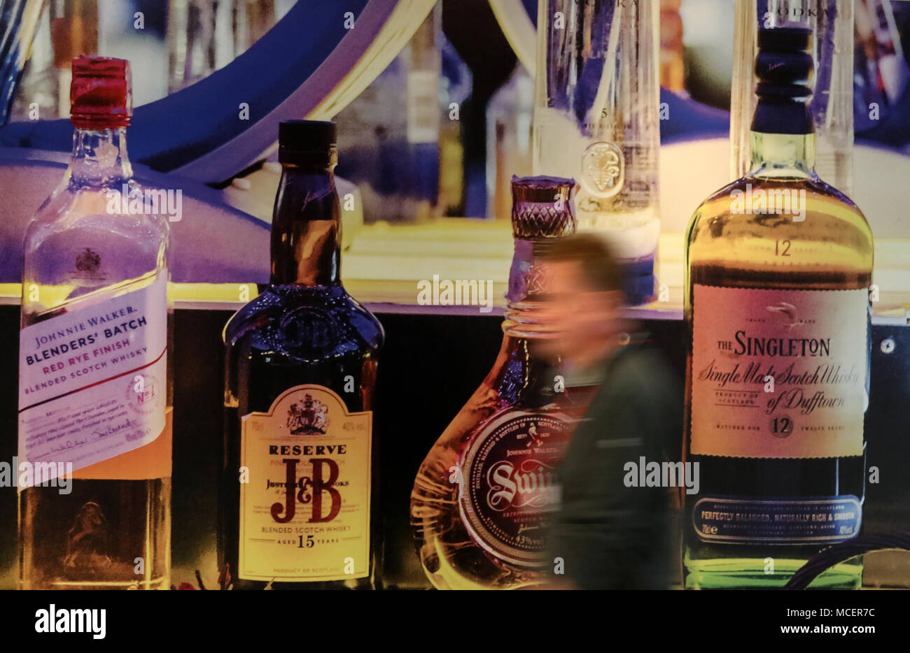 A person walks past Diageo owned whiskies on a poster at their