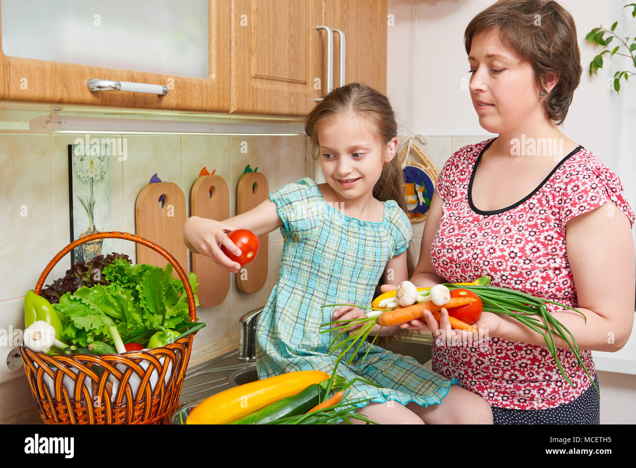 Mother and daughter cooking. Basket of vegetables and fresh fruits