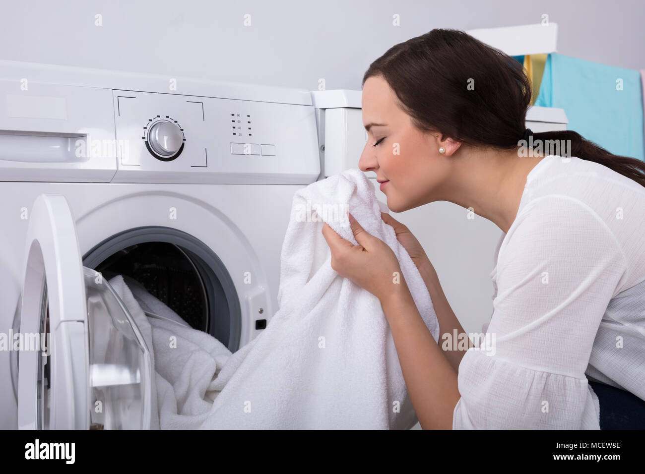 Close-up Of A Young Woman Smelling White Cloth After Washing In Washing Machine Stock Photo