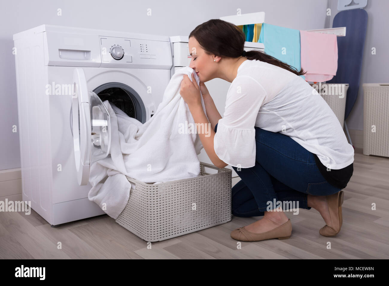 Close-up Of A Young Woman Smelling White Cloth After Washing In Washing Machine Stock Photo