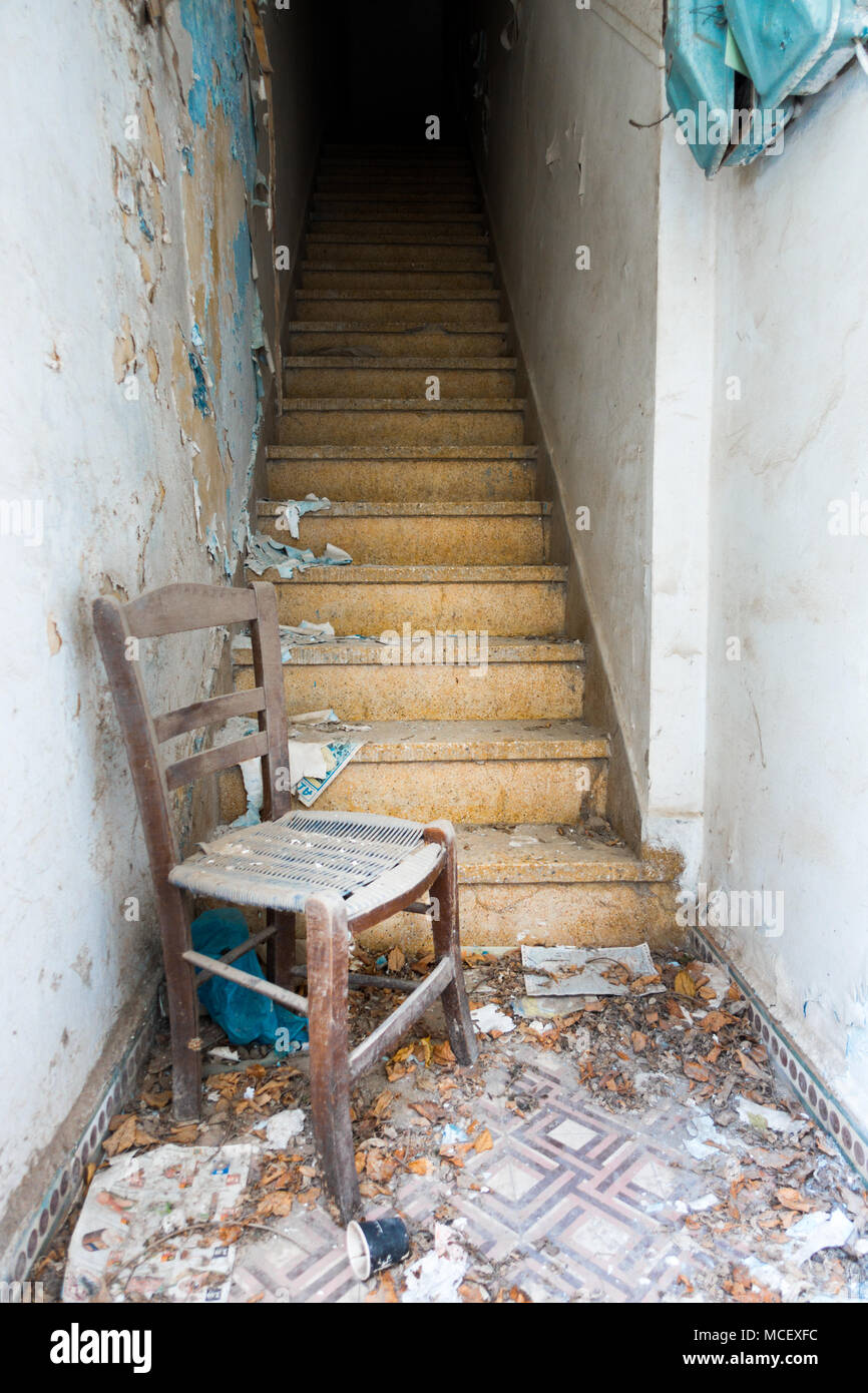 Wooden chair with ruined wall and staircase of old building Stock Photo