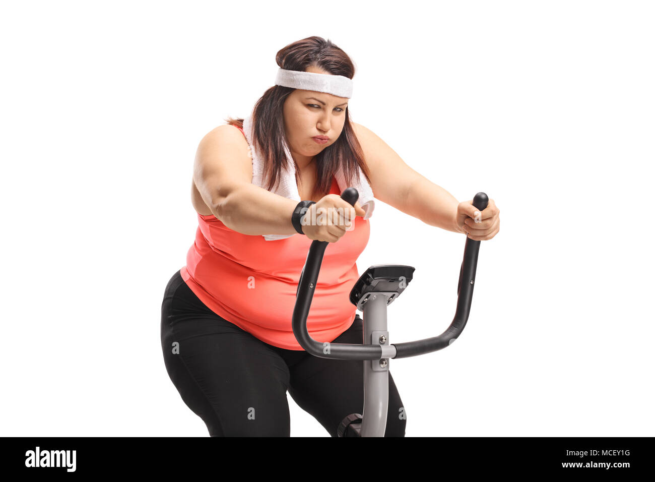 Exhausted overweight woman exercising on a stationary bike isolated on white background Stock Photo