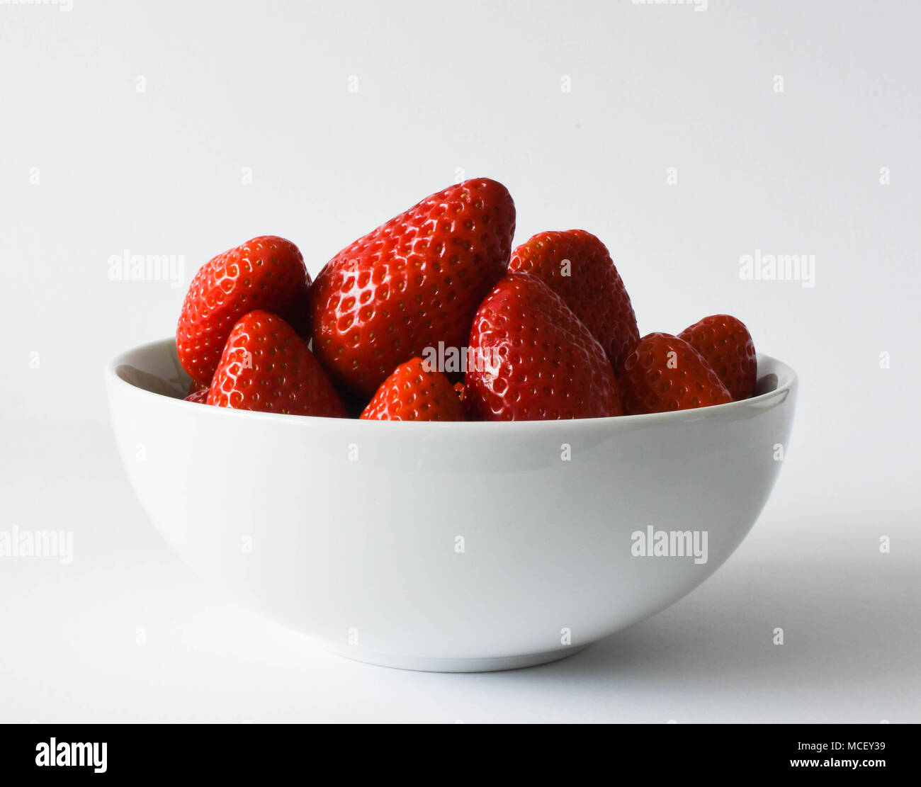Strawberries in a white dish on a plain white background Stock Photo ...