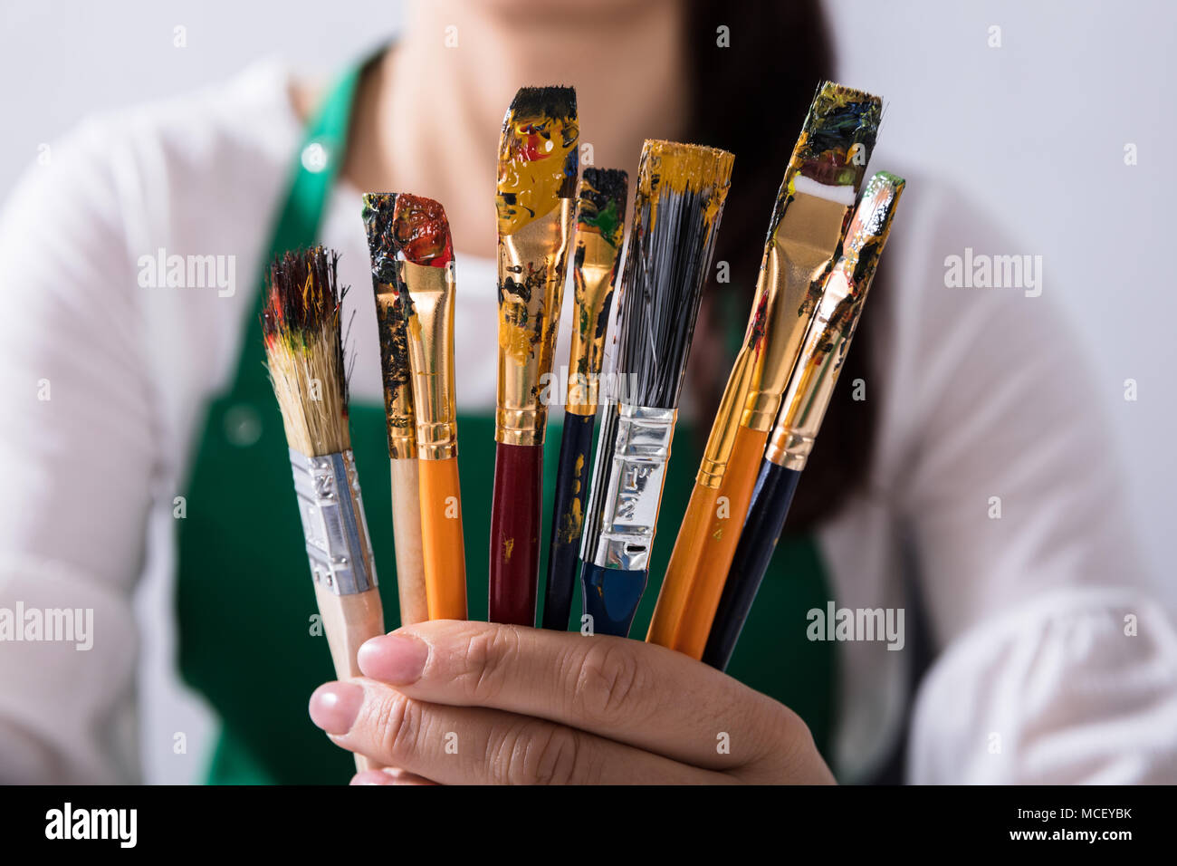 Close-up Of Various Paintbrushes In Front Of Female Artist Stock Photo