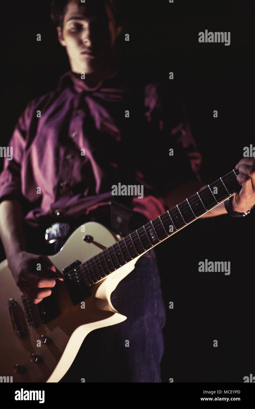 Guitarist playing electric guitar on black background. Retro style Stock Photo