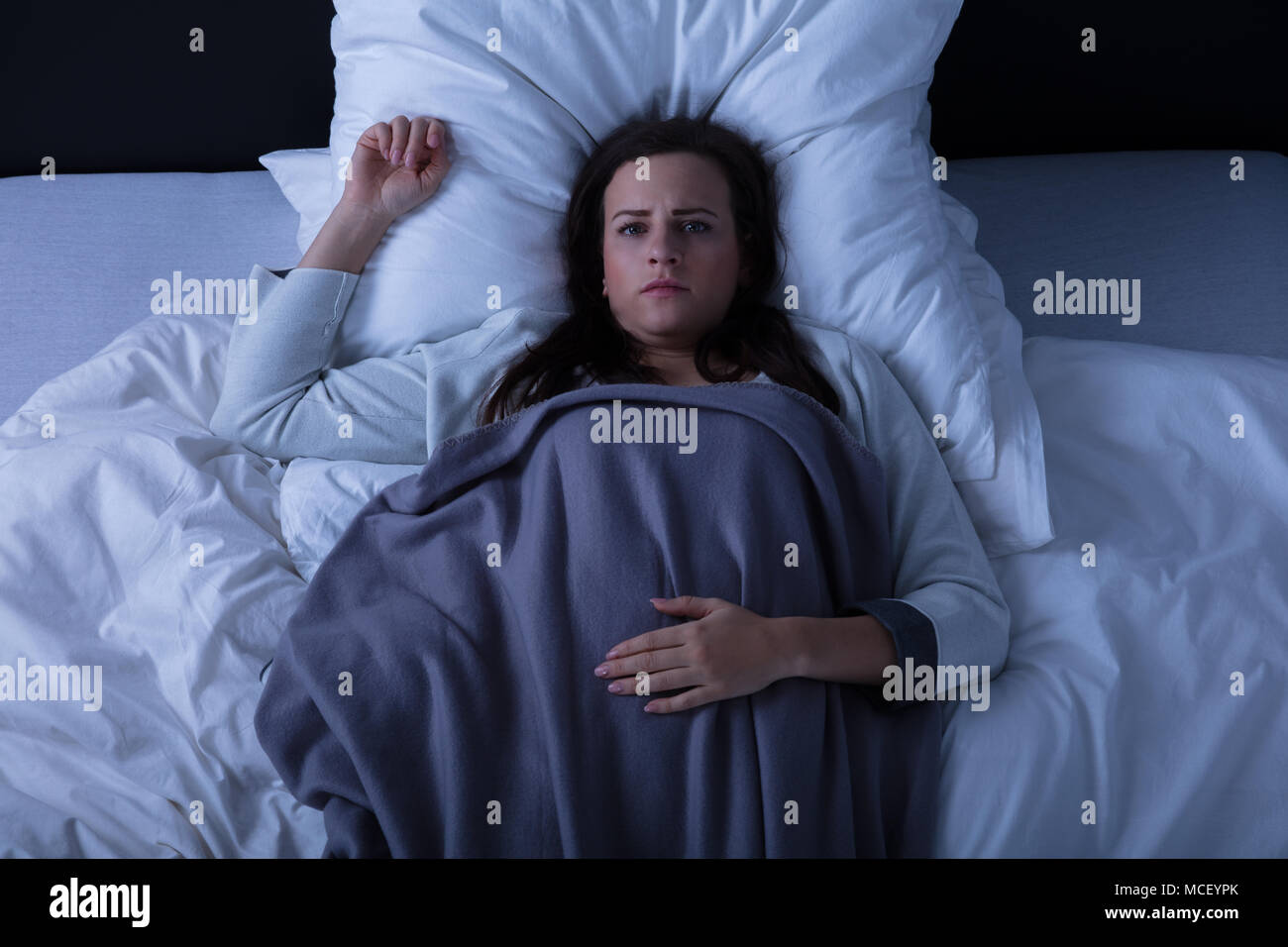 Elevated View Of A Sad Young Woman Lying On Bed Stock Photo