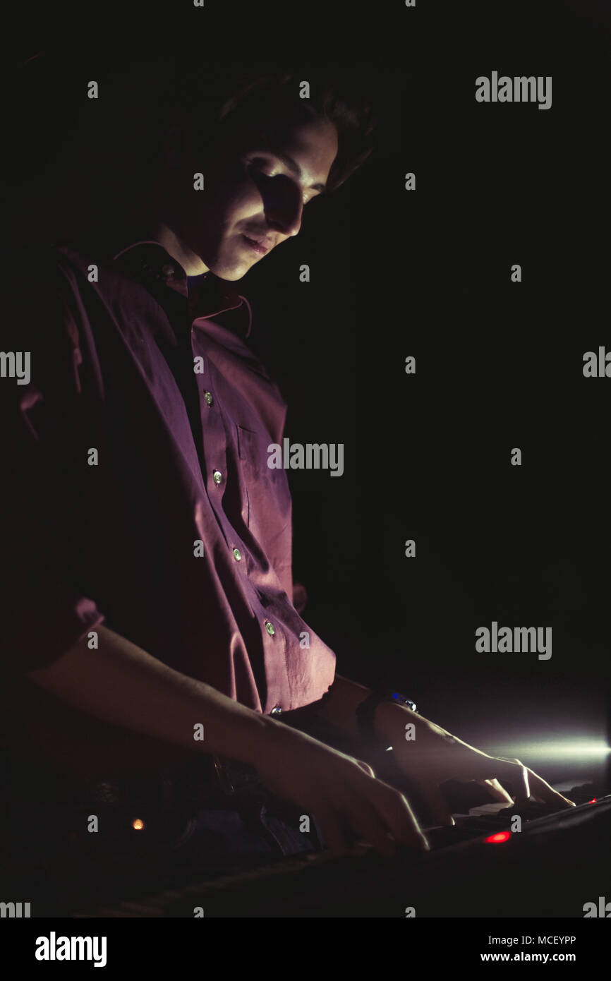 Guy playing on synthesizer keyboard on black background Stock Photo