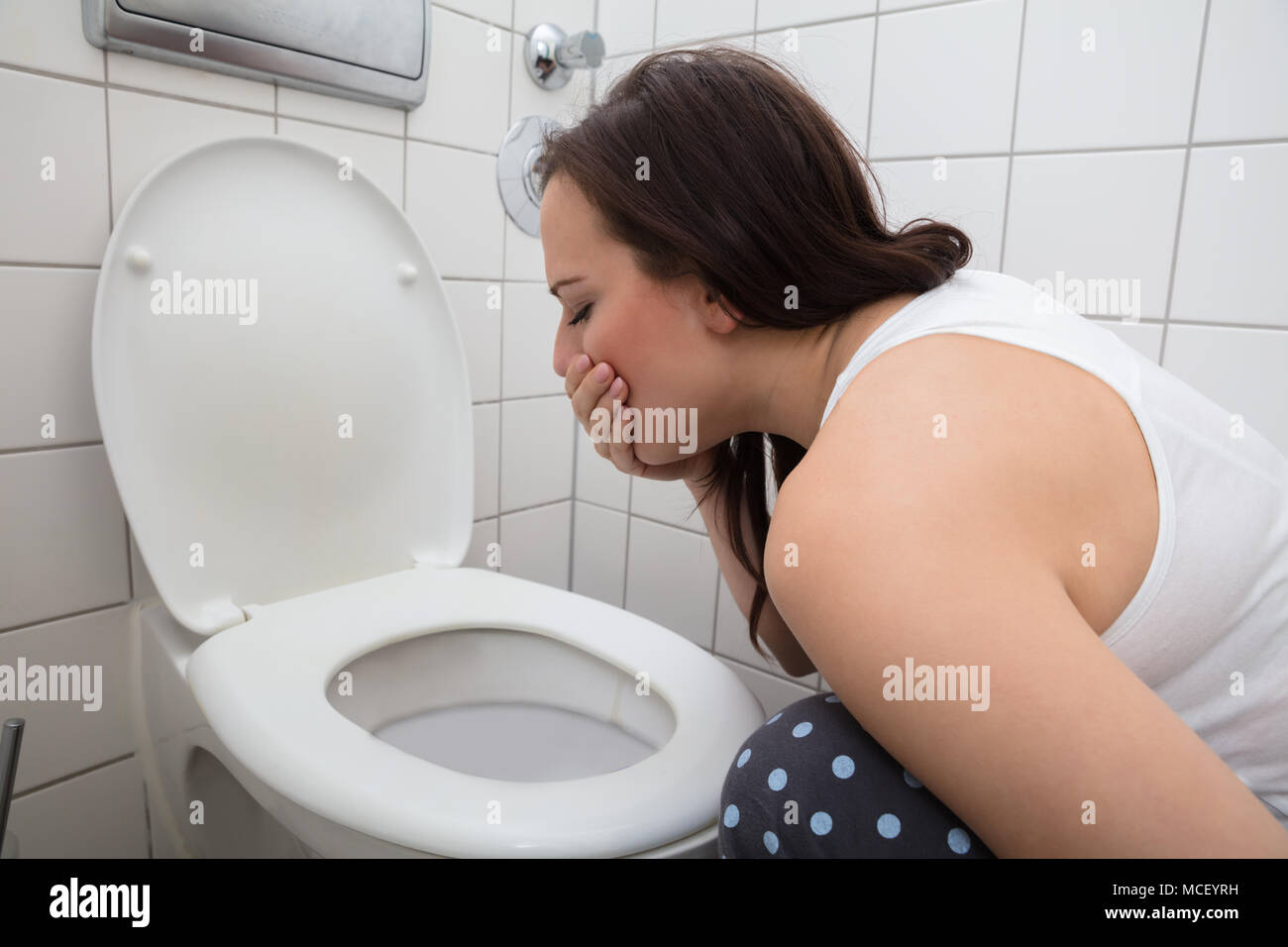 Close-up Of A Young Woman Vomiting In Toilet Bowl Stock Photo