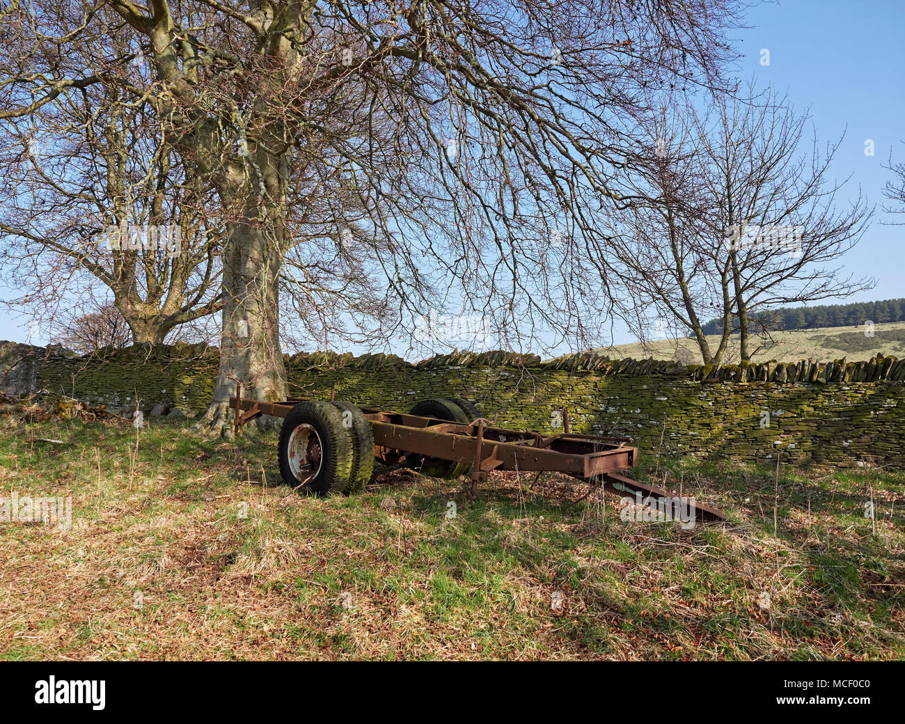 The Bare Chassis of a Four Wheel Trailer lies abandoned in a cornerof a