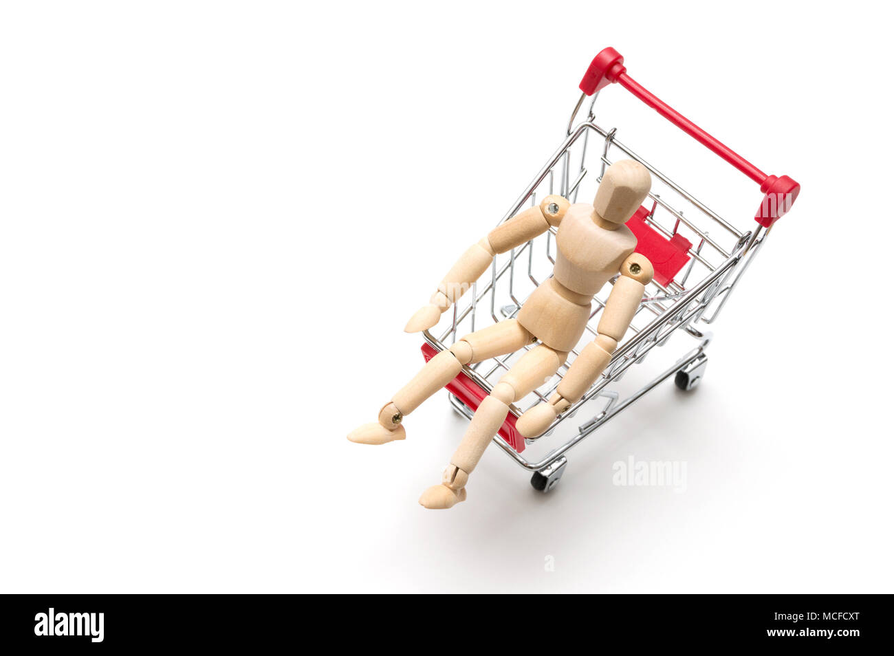Wooden doll and shopping cart on white background : economy concept Stock Photo