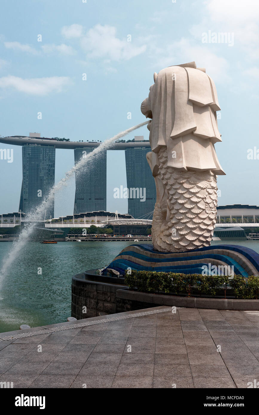 The flowing water spout of the landmark Singapore Merlion with Marina Bay Sands in the hotel in the background. Stock Photo