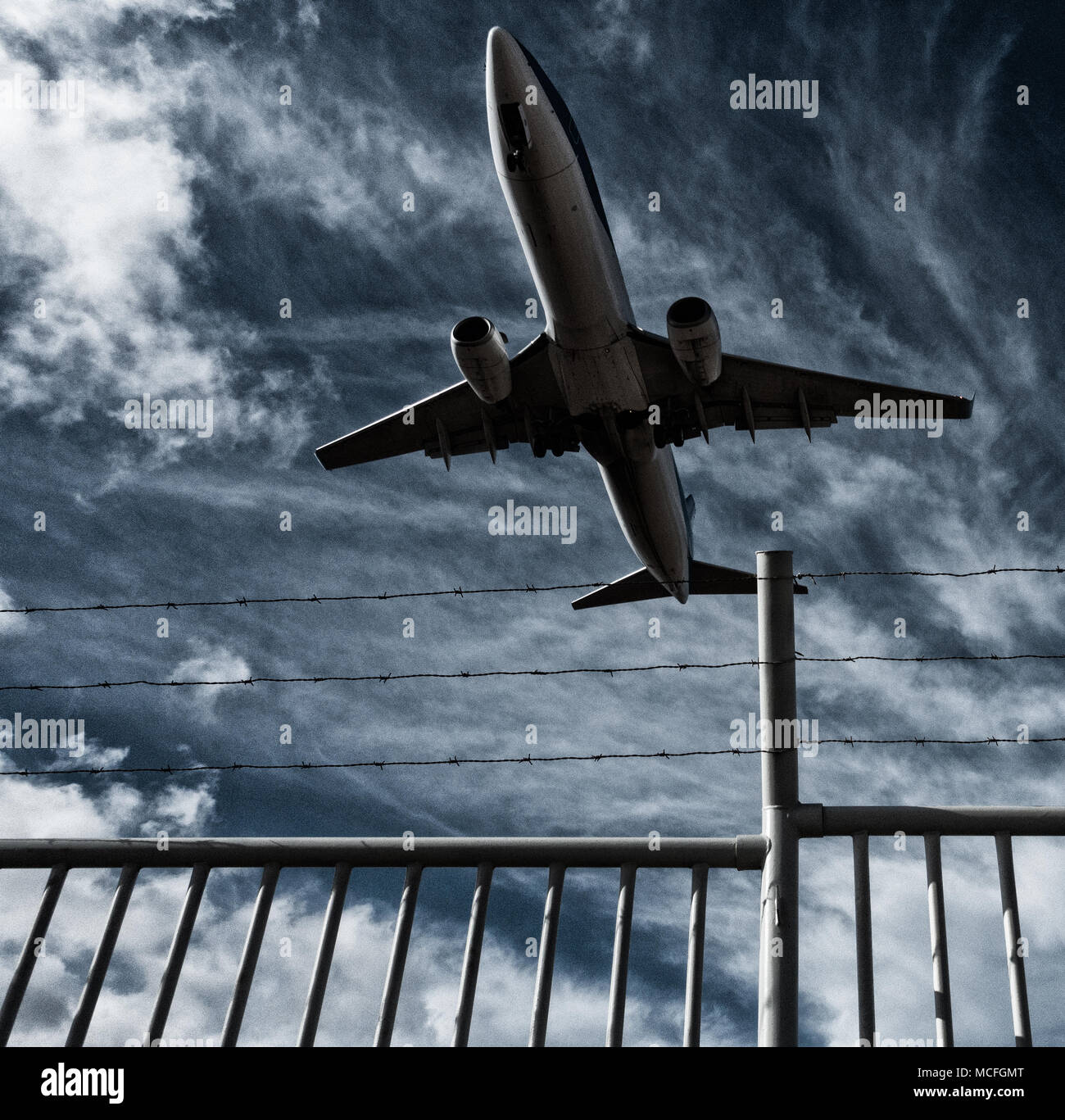 Low flying aircraft/airplane flying over barbed wire fence. Concept image: no fly zone, Ukraine Russia conflict, war Stock Photo