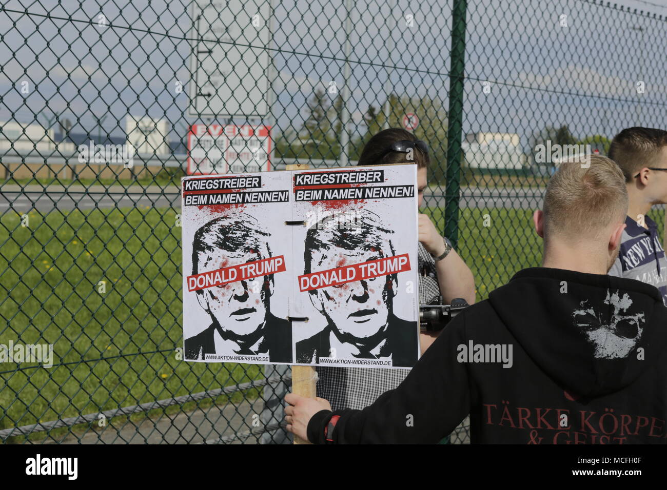 A protester holds a sign that reads 'Call warmonger by his name - Donald Trump'. Members of the right-wing Jungen Nationalisten (Young Nationalists), the youth organisation of the National Democratic Party of Germany (NPD), and the Generation Identity protested outside the Lucius D. Clay barracks in Wiesbaden-Erbenheim, where the headquarters of United States Army Europe (USAREUR) is located, against the recent military attacks of the US, Great Britain and France on Syria. The protest was attended by the chairman of the NPD in Hesse, Daniel Lachmann, and the vice-chairman of the NPD in Baden-W Stock Photo