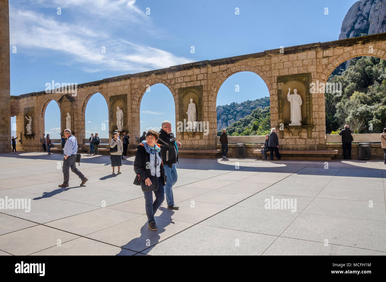A stone wall at Santa Maria de Montserrat Abbey in Spain featuring archways and sculptures depicting religious figures or scenes. Stock Photo