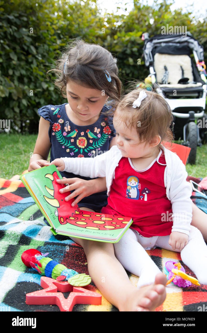 Big sister reading to her toddler sister. Stock Photo