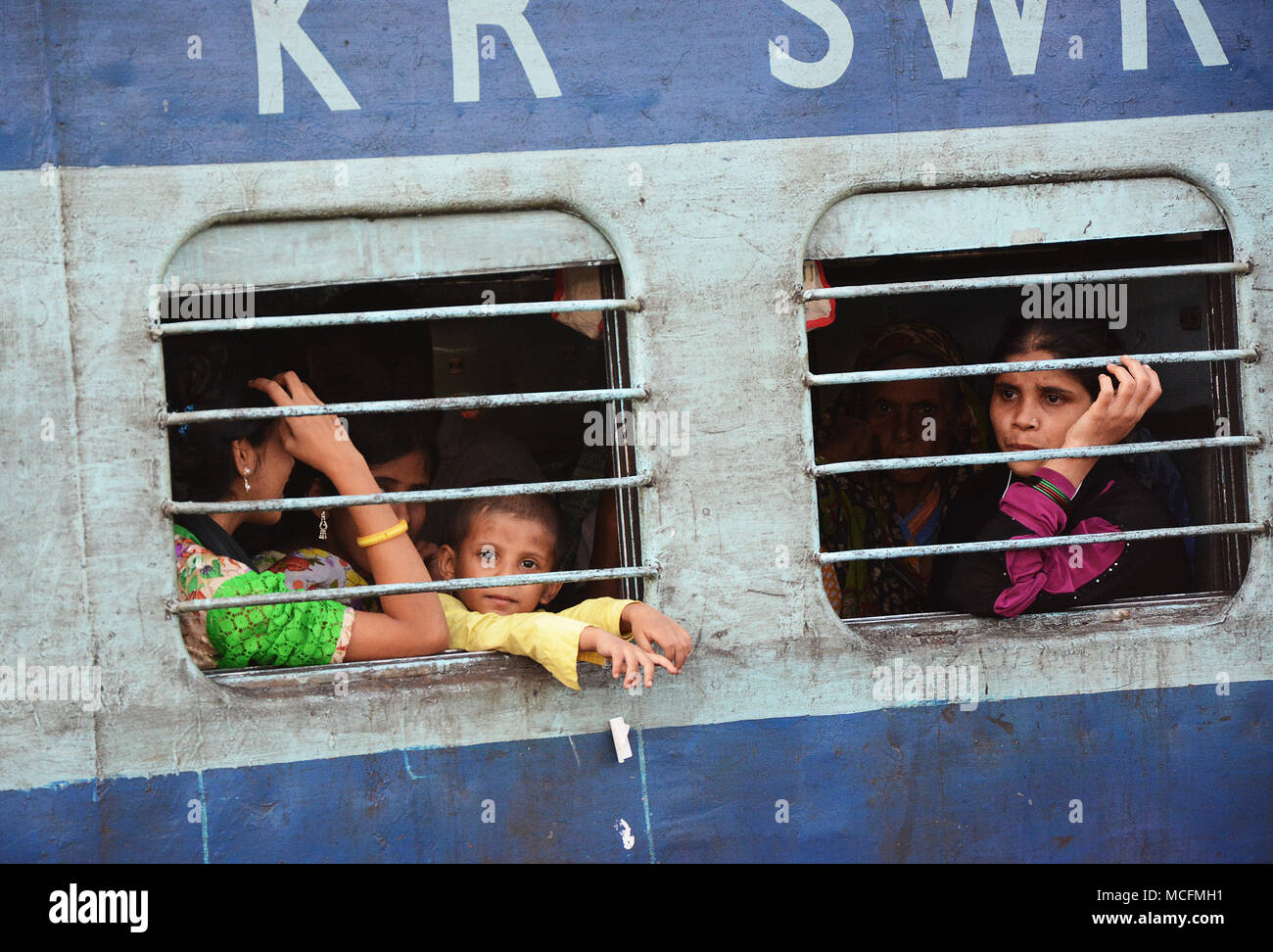 A family seen through the bars of a window on a train in India, Mumbai bound Stock Photo