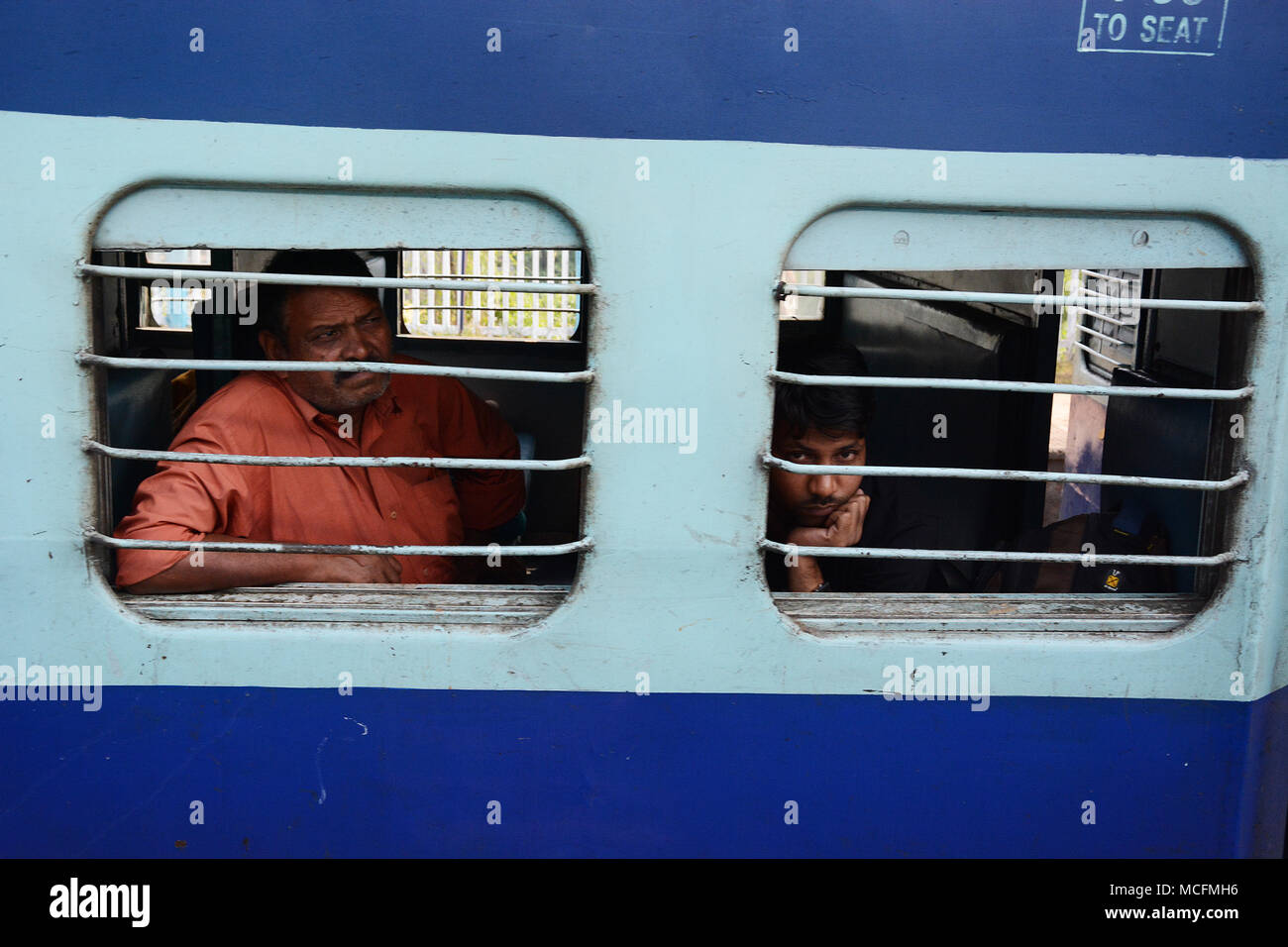 A man and a teenage boy travelling on a train in India Stock Photo