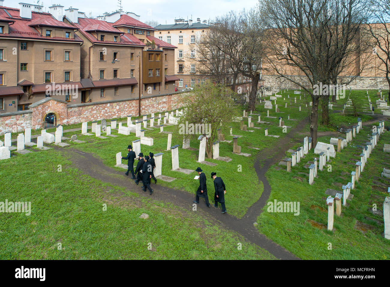 Krakow, Poland - April 11, 2018: A group of orthodox Jews in black visiting Remuh cemetery at still active Remah Synagogue in old historical Jewish Ka Stock Photo