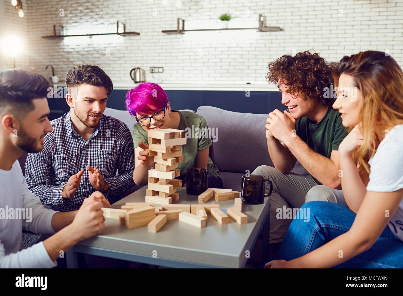 A cheerful group of friends play board games in the room. Stock Photo