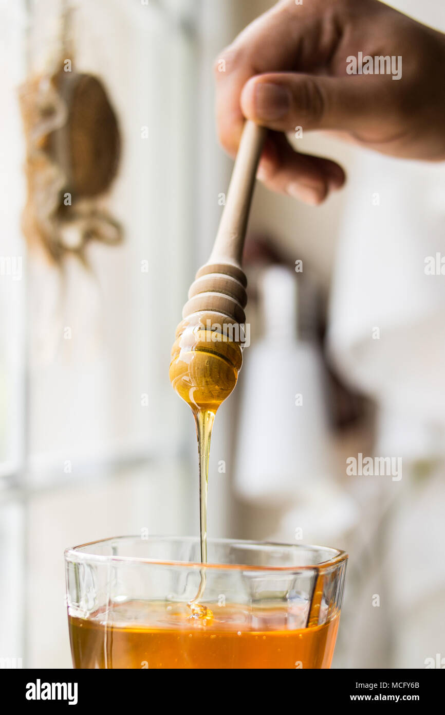 Honey dripping with wooden dipper Stock Photo