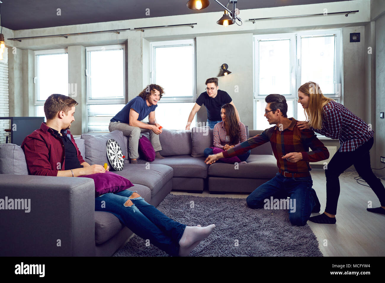 A cheerful group of young people play board games in the room. Stock Photo