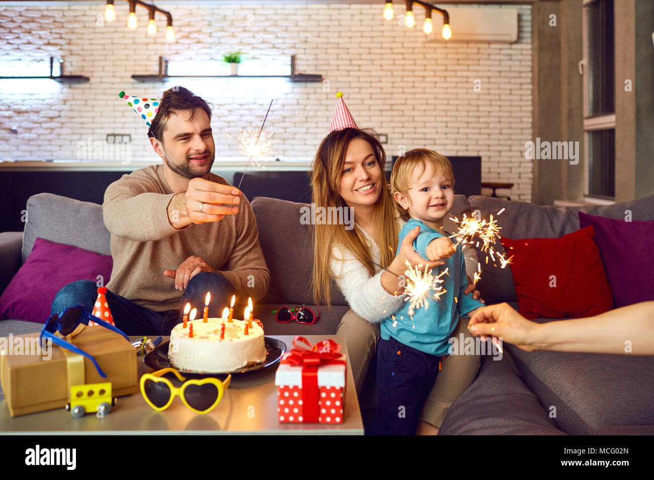 Parents with a cake with candles congratulate their child on his birthday. Stock Photo