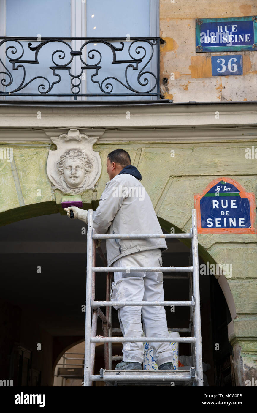 A decorator at work on the facade of an old building on the Rue de Seine, Paris, France, Europe Stock Photo
