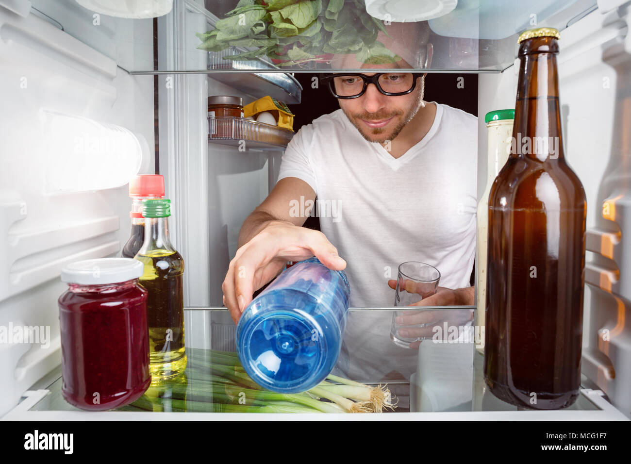 https://c8.alamy.com/comp/MCG1F7/man-grabbing-a-water-bottle-in-the-fridge-MCG1F7.jpg